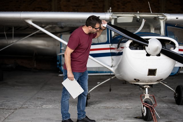 Pilot doing a preflight check on a light aircraft in a hangar